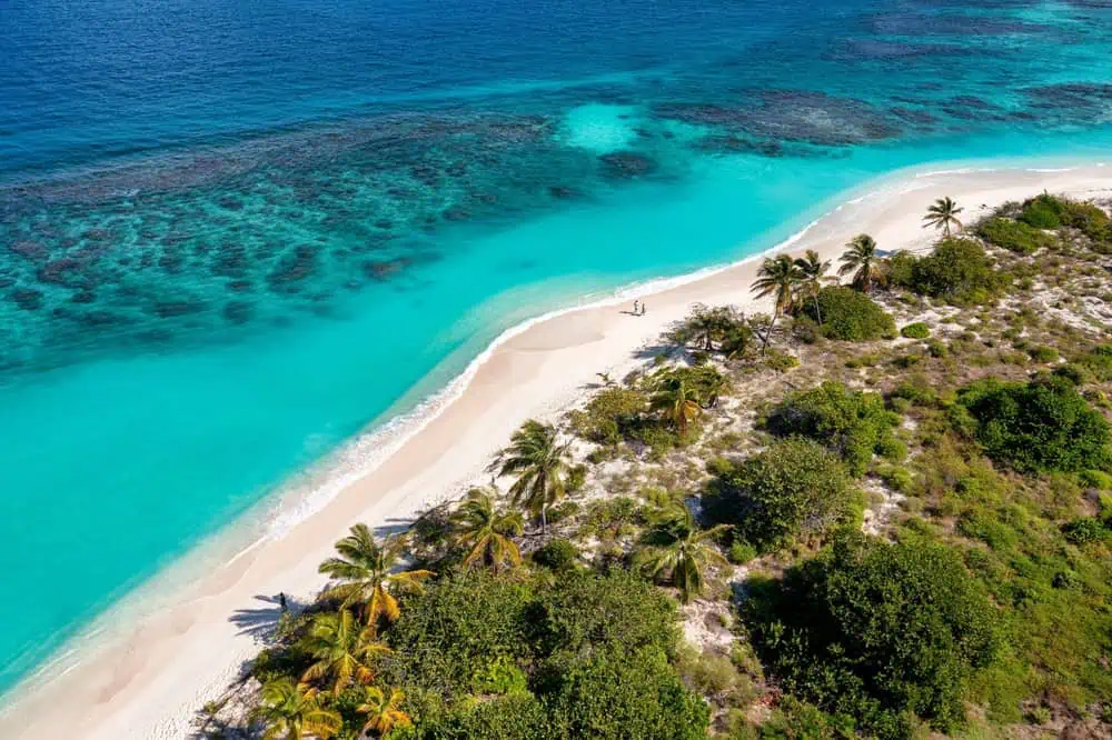 Aerial view of a white-sand beach and turquoise reef water on the Anguilla coastline