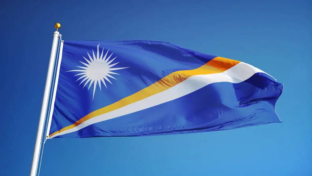 Flag of the Republic of the Marshall Islands waving against a clear blue sky